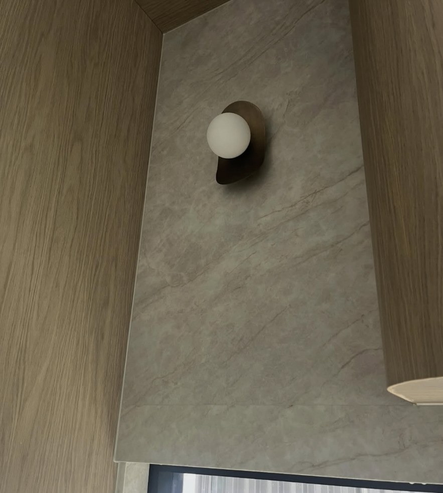 Marble splashback and timber joinery detail in Austral with a neat silicone joint around the wall light