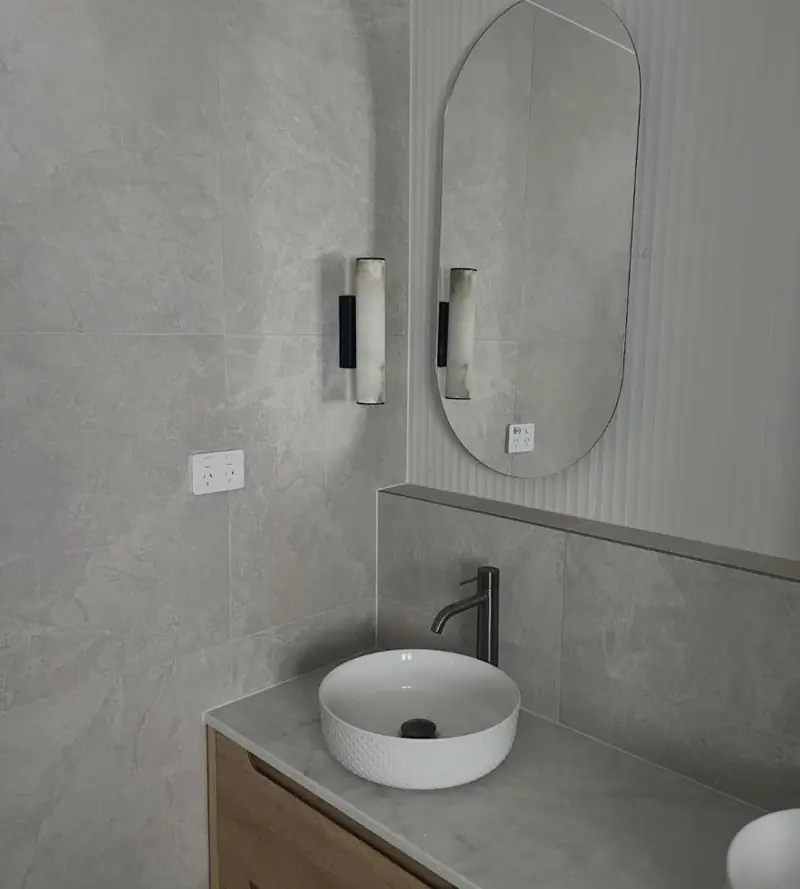 Bathroom vanity with stone benchtop and tiled walls sealed with clean silicone joints