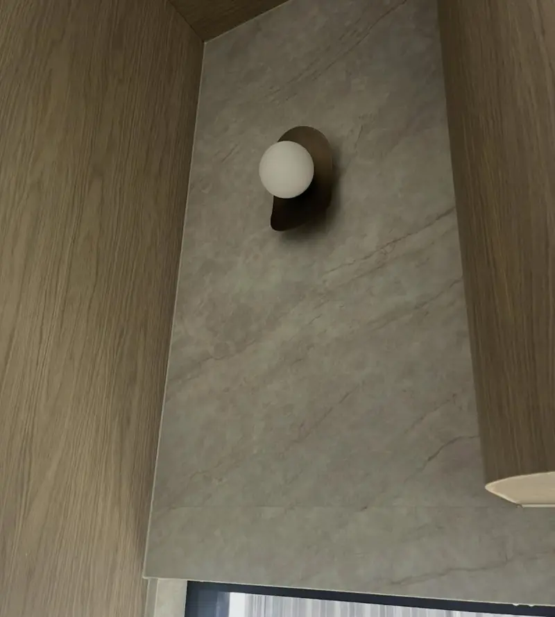 Marble splashback and timber joinery detail in Austral with a neat silicone joint around the wall light