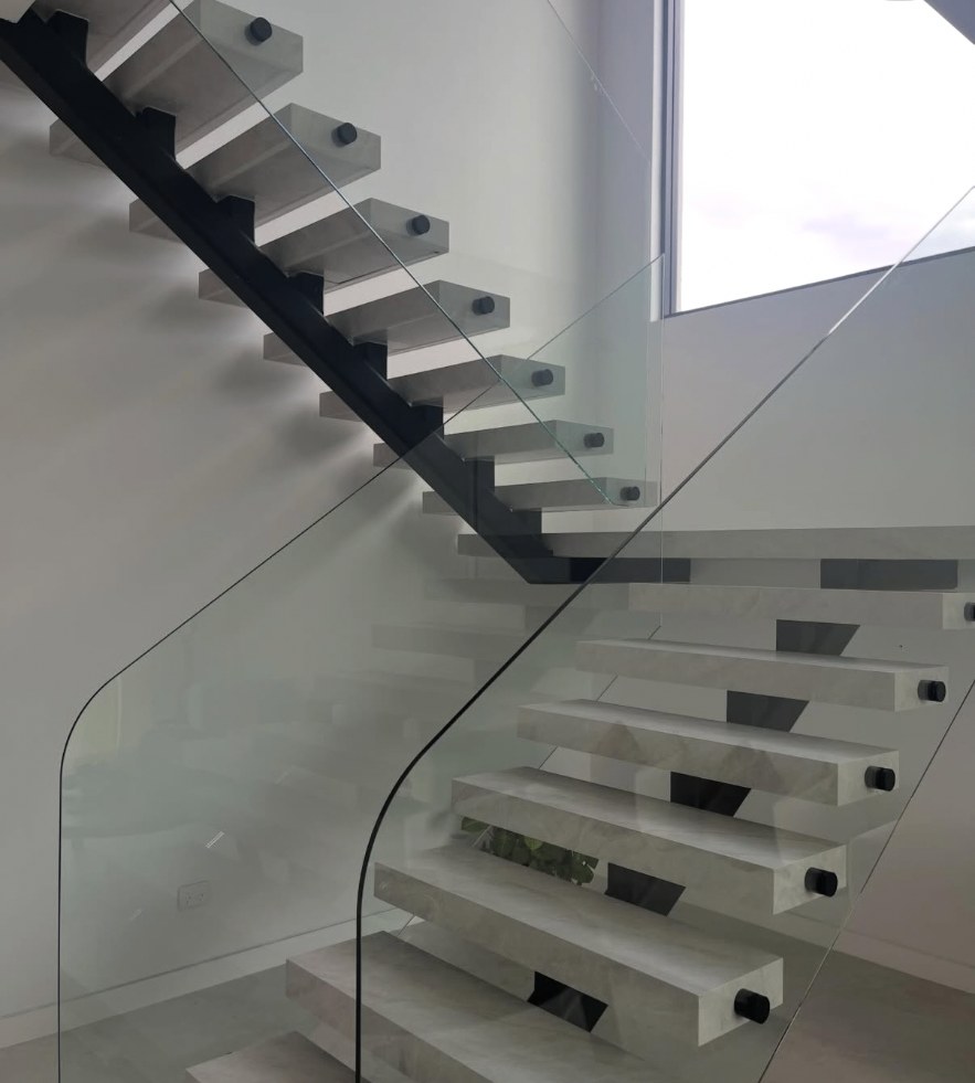 Floating stone staircase with glass balustrade in Austral, treads and walls sealed with clean silicone lines
