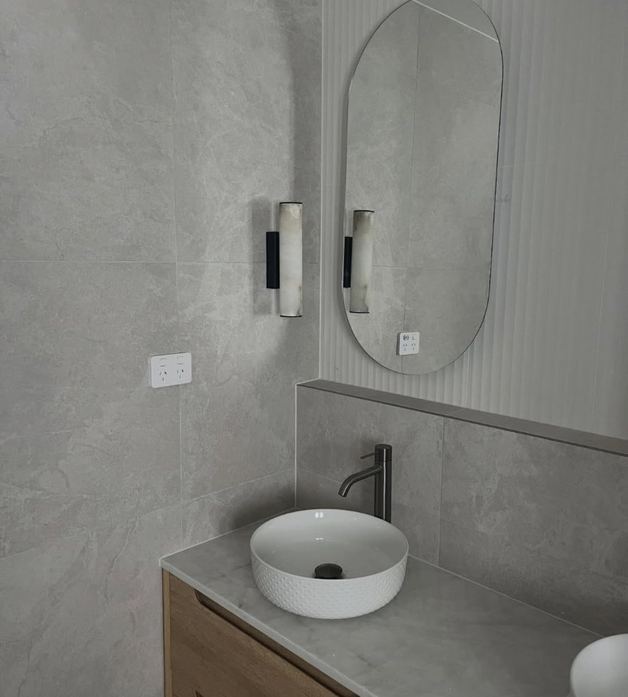 Bathroom vanity with stone benchtop and tiled walls sealed with clean silicone joints
