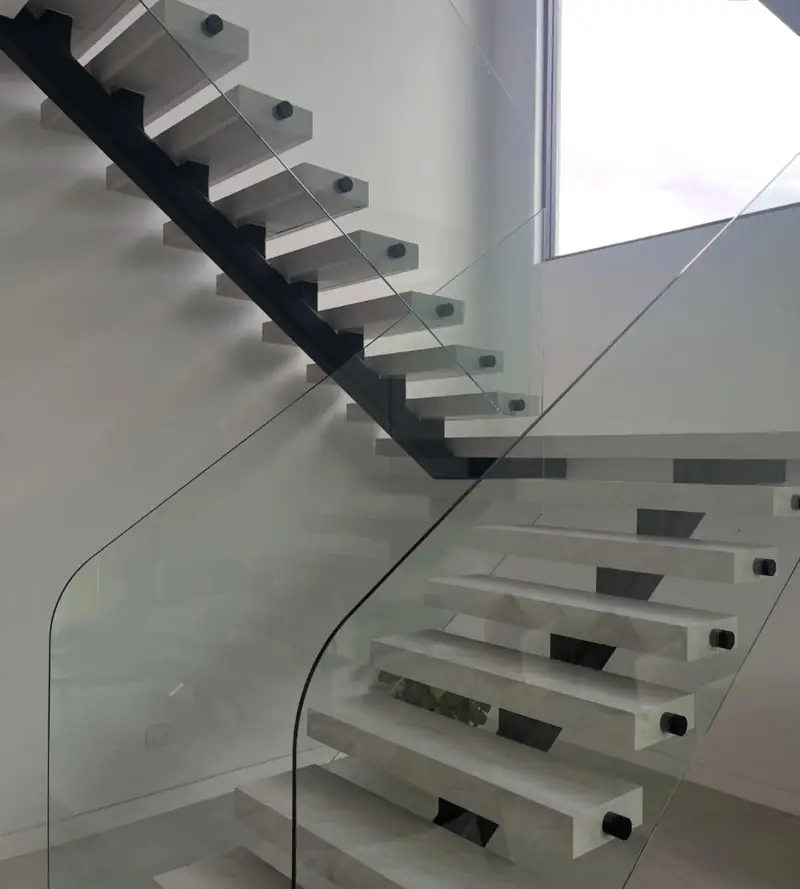 Floating stone staircase with glass balustrade in Austral, treads and walls sealed with clean silicone lines